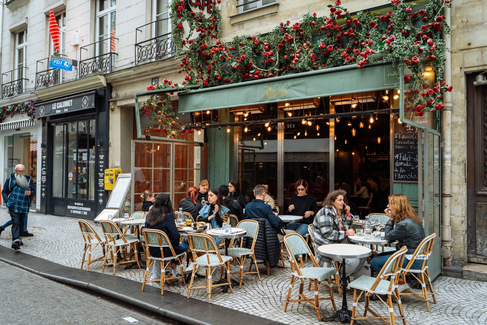 A sunny French café terrace with a carafe of water and a chalkboard menu