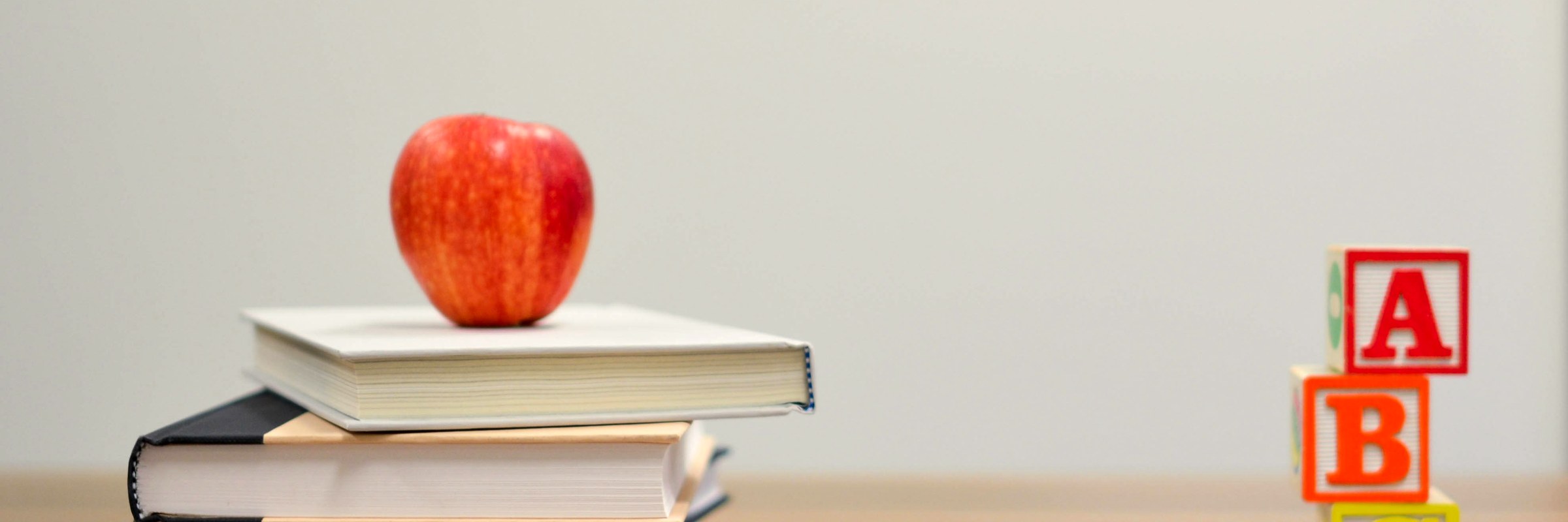 An apple on a stack of books beside ABC alphabet blocks
